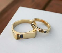 two gold wedding rings sitting on top of each other