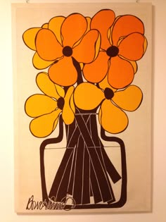 an orange and black vase with yellow flowers on white paper in front of a wall