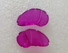 two pieces of purple plastic sitting on top of a white surface with small bubbles in the middle