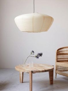 a wooden table sitting next to a wicker chair with a vase on top of it