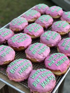 pink frosted doughnuts with green icing on a cooling rack that says happy birthday