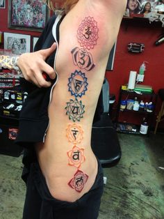 a woman showing off her back tattoo with seven chakras