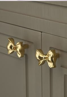 two gold bow knobs on the front of a kitchen cabinet