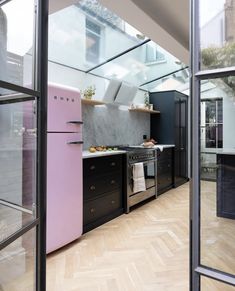 a kitchen with black cabinets and pink refrigerator freezer next to an open glass door