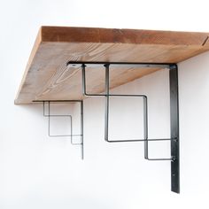 a wooden shelf with metal brackets hanging from it