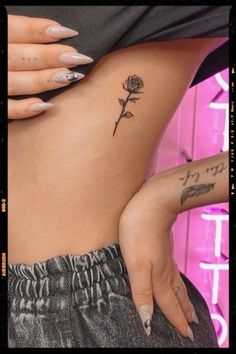 a woman's stomach with tattoos on it and a rose tattooed on the side