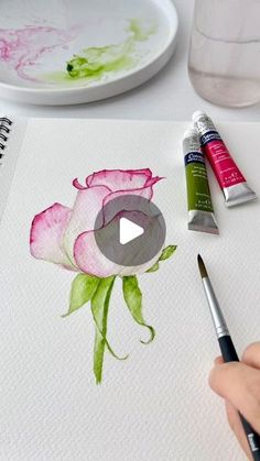 someone is painting a rose with watercolors on paper