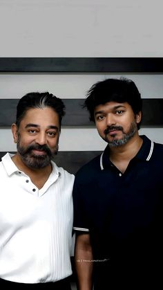 two men standing next to each other in front of a black and white striped wall