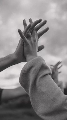 black and white photograph of two people's hands reaching up to grab something in the air