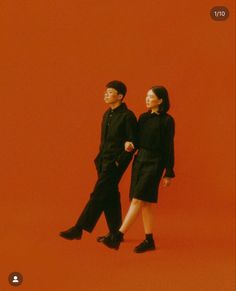 two people standing next to each other on a red background