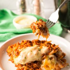 a white plate topped with lasagna covered in cheese and sauce next to a green napkin