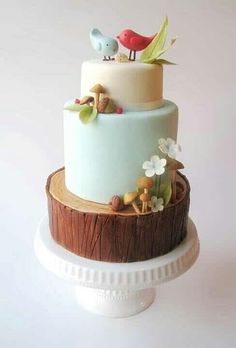 a three tiered cake decorated with birds and flowers on top of a tree stump