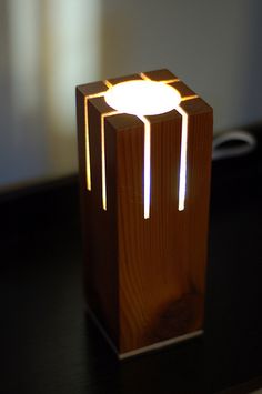 a wooden table with a lamp on it and a cell phone in the back ground