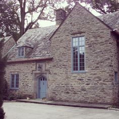 an old stone house with two windows and a blue front door is shown in the foreground