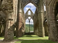 the inside of an old church with stone arches and grass on the ground below it