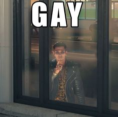 a man standing in front of a window with the words gay written on it's side