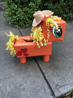 an orange toy horse with a straw hat on it's head and yellow streamers around its neck