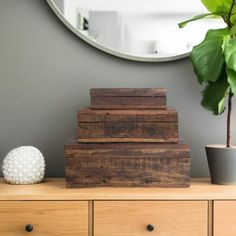 a wooden box sitting on top of a dresser next to a potted plant and mirror