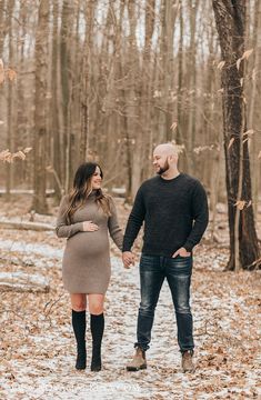 an engaged couple holding hands and walking through the woods