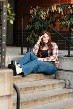 a woman sitting on the steps with her hand in her hair and looking at the camera