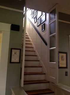 a staircase with pictures on the wall next to it and framed photos hanging on the wall