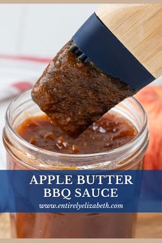 an apple butter bbq sauce in a glass jar with a wooden spoon sticking out of it