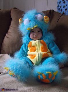 a baby in a blue monster costume sitting on a couch