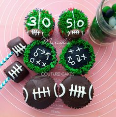 cupcakes decorated to look like football balls with numbers on them and grass in the middle