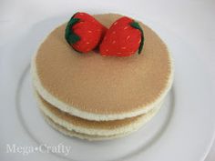 two strawberries sitting on top of some kind of cake that is made out of pancakes