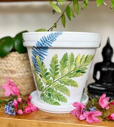 a potted plant sitting on top of a wooden table next to pink and purple flowers