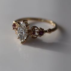 a close up of a ring on a white surface with a light colored diamond in the middle