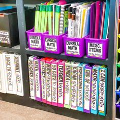 a book shelf filled with lots of books next to bins full of pens and pencils