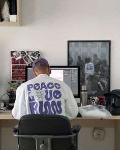 a man sitting in front of a computer on top of a desk next to a chair