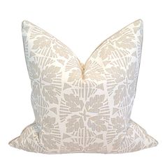 a white and beige pillow with an intricate design on the front, sitting on a white background