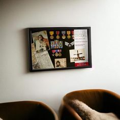 two brown chairs sitting next to each other in front of a wall with pictures on it