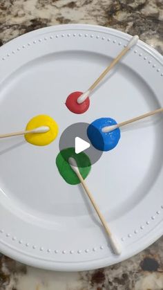 four toothpicks on a white plate with colored sticks