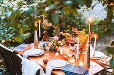 an outdoor table set with plates and candles