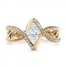 a yellow gold ring with a pear shaped diamond in the center and an intricate band around it