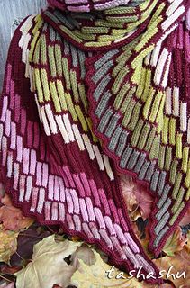 a knitted shawl sitting on top of leaves