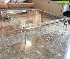 a glass coffee table sitting on top of a marble floor