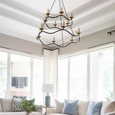 a living room with couches, chairs and a chandelier hanging from the ceiling