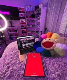 a cell phone sitting on top of a bed next to a stuffed animal and laptop