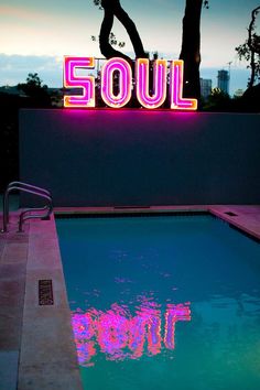 a pool with the word soul lit up in neon lights next to it at night