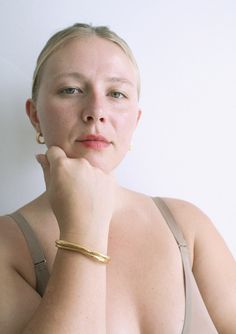 a woman with her hand on her chin looking at the camera while wearing a bra