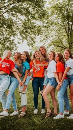 a group of young women standing next to each other on top of a lush green field