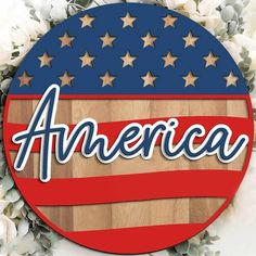 an american flag with the word america on it in front of white flowers and leaves