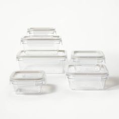 six glass containers with lids are stacked on top of each other and one is empty