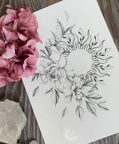 some flowers are sitting on a table next to a piece of paper that has been drawn