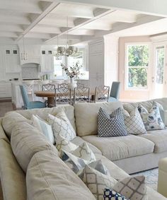 a living room filled with white furniture and lots of pillows on top of it's couches