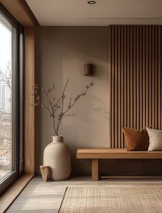 a wooden bench sitting in front of a window next to a vase filled with flowers